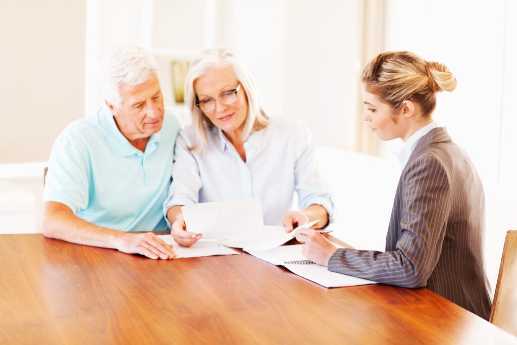 Senior couple consulting a financial advisor over documents.