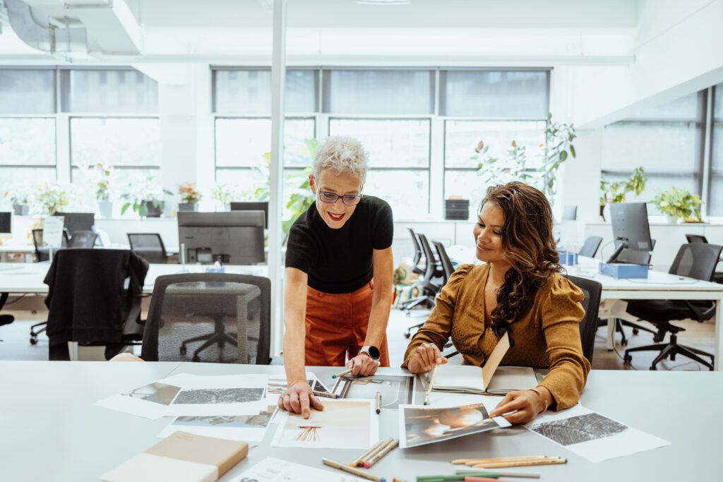 Two women collaborating on a project in a bright office space.